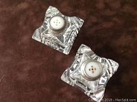 Top view of two antique salt and pepper shakers showing clear cut crystal bases with star pattern and white pierced tops.