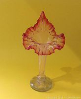 Front and side views of cranberry-hued bloom-shaped hand blown glass vase with clear stem and base