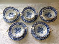Five Paragon two-handled consomme bowls arranged on matching underplates, displaying blue floral pattern and gold rim accents.