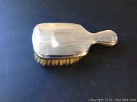 Top side of the Birks sterling silver hair brush showing smooth silver surface with light scratches and engraved linear patterns.