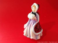 Front and left side view of a porcelain figurine titled Miss Susan, showing detailed coloring and bonnet.