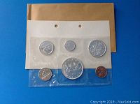 Set of six 1963 Canadian coins sealed in plastic sheets on cardboard with a brown envelope in background.