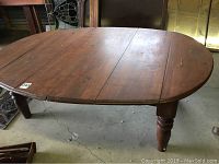 Full view of the oval wooden table showing its shape, legs, and surface condition.