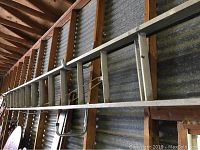 Long aluminum extension ladder mounted on a wall, showing the whole length from ground to top end.