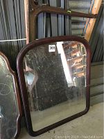 Front view of the wood framed wall mirror with a rounded rectangular shape and reflective surface with visible wear.