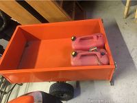 Top view photo of orange lawn wagon showing empty cargo bed with two red gas cans inside