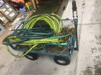 Photo of metal garden wagon loaded with two coiled garden hoses, showing mesh sides and tires.