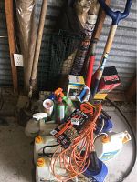 Overview of garden tools and supplies showing shovels, burlap wraps, spray bottles, extension cord, and chemical containers