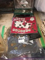 Jewellery box, coin sets, and loose coins on a wooden surface.