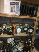 Four pairs of rain boots (sizes 8, 9, 10) lined up on shelf and solar powered lamps in boxes and two lamps on the shelf below.
