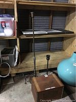 Tall retro floor lamp with metal base shown standing next to a small table lamp base and a wooden box on the floor.