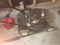 Full side view of Craftsman Kohler lawn mower with gas can beside it, mounted on white wheels, showing some grass residue on wheels and mower body.
