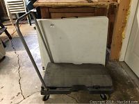 Folding table and plastic cart folded and standing upright together.