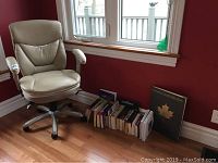 Chair and books positioned under window against red wall