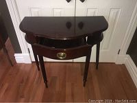 Image of front view of wooden hall table with semicircular top and turned legs.