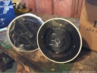 Two round in-wall speaker assemblies with paint masks on workbench