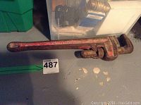 Large used pipe wrench against a floor background