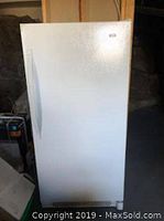 Front view of white Kenmore upright freezer on concrete floor