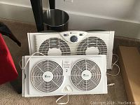Two Westinghouse window fans placed side by side, showing the front grille and control panel.