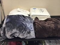 Photo showing two blankets folded along with king size mattress pad behind them