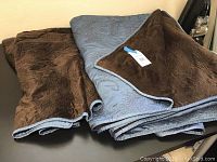 Folded blue reversible king quilt showing brown plush backing and stitching detail on blue side