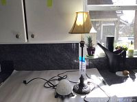 Photo of the two lamps placed on a countertop near a window, showing entire lamps including cords and power plugs.