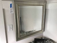 Full view of square wall mirror showing silver painted frame and reflective surface.
