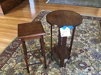 Two wooden side tables on a patterned area rug. One is rectangular and taller, the other is round and shorter with a lower shelf.