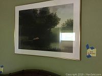 Full view of framed picture showing the art and white matte inside the gold frame with surrounding green wall background.