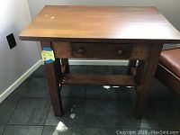 Front view of wooden square antique parlor table with one drawer and two round knobs, medium brown finish.