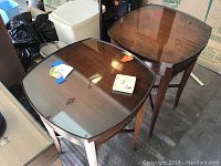 Two antique wooden nightstands with dark wood finish and glass tops with some items placed on them, top view.