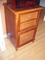 Front view of wooden file cabinet with woven wicker drawer fronts