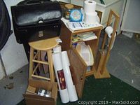 Overview of stool, cupboard, briefcase, folding chairs, tissue holder, paper towels, and household items in box and on cupboard.