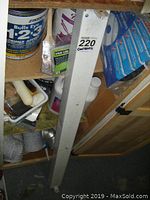 Partial cans of Bull's Eye primer paint, Shur-Line edger, Quickie steel handle, assorted paints on shelf with painting accessories.