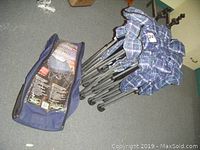 Photo of the folded blue plaid framed portable air bed next to navy blue carrying bag with product label.