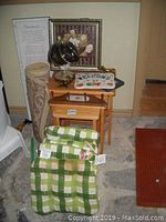 Photo of solid wood nesting tables, rolled carpet runner, framed floral print, decorative lamp, ceramic 'Welcome' plate, and cushions.