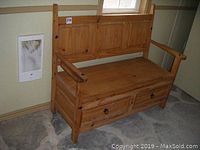 Front view of pine wooden bench showing two storage drawers beneath seat, with metal ring pulls and vertical slat backrest.