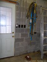 Industrial straps hanging on a wall next to a door in a workshop setting.