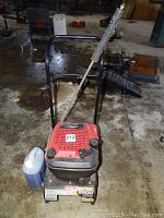 Front view of pressure washer with detergent jug and wand attached on two-wheeled frame