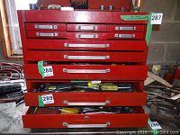View of red metal tool chest open drawers showing condition and size, with some tools inside drawers providing scale but contents not included.