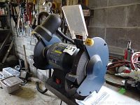 Front view of Mastercraft bench grinder showing grinding wheels, power switch, adjustable work light, and eye shields.