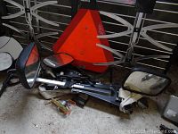 Top angle photo showing TV antenna, vehicle mirrors, and orange slow vehicle triangular sign clustered together on concrete floor.