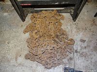 Rusty heavy metal chain laid on floor next to workbench legs