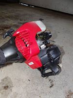 Engine and pull start of Yard Machines gas trimmer, showing red and black housing with visible cord