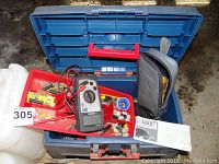 Blue plastic toolbox open showing assorted electrical connectors, parts, tape, and hand tools including a Mastercraft multimeter inserted in the box and manual on top.