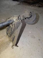 Grass trimmer head with guard attached to shaft, showing used condition and protective shield.