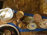 Overview of assorted plates, platters, and glassware on blue striped cloth