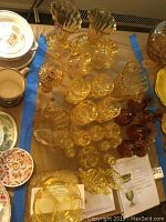 Overview of the collection showing multiple yellow and amber glass pieces including stemware, vases, decanters, and the mini oil lamp.