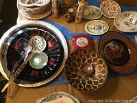 Overview photo of metal trays, composite platters, ceramic dishes including Wedgwood Jasperware trinket dish, and ladles arranged on a table