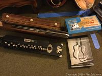 Lot overview including Japan Banjo, music stand case, string collection, Dremel motor box, and guitar construction book.